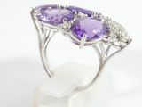 a close up of a ring with two purple stones on a white marble base