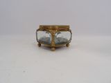 a small glass box with a gold lid on a table