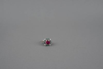 une bague ornée d'un seul rubis et de diamants, posée sur une surface grise