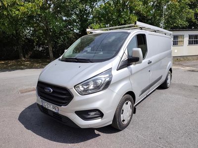 une camionnette blanche garée sur un parking avec des arbres en arrière-plan