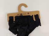 a black panties hanging on a hanger on a white wall