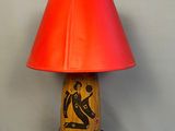 a wooden table lamp with a red shade on top of it