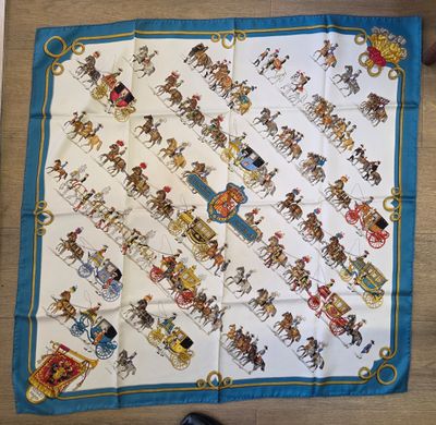un gros plan sur un foulard carré bleu et blanc orné de chevaux et de calèches