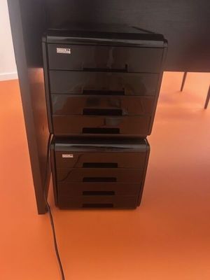 deux tiroirs noirs situés sous un bureau sur lequel se trouve un ordinateur