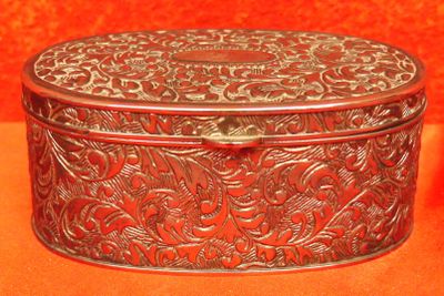 une vieille boîte en métal argenté ornée d'un motif floral