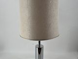 une lampe de table chromée surmontée d'un abat-jour beige