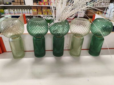 quatre vases en verre vert sont alignés sur une étagère