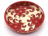 a red bowl with a design on it on a white surface