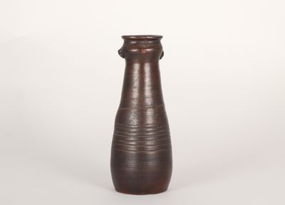 un vase brun posé sur une surface blanche