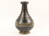 a black and gold vase sitting on a white surface