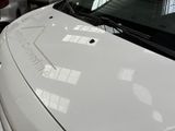 a white car parked in a garage with a sticker on the hood