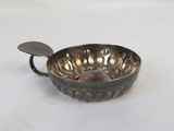 an old silver bowl with a handle on a white surface