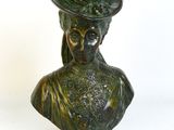 un buste en bronze représentant une femme coiffée d'un chapeau