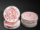 several white plates with red designs are stacked on top of each other