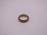 gros plan d'une bague en or sur une surface blanche