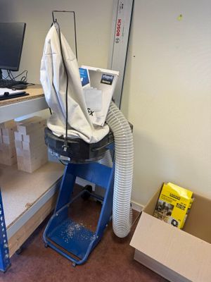 a computer on a desk with a vacuum in the corner of the room