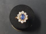 un gros plan d'une bague en or sertie d'une pierre bleue entourée de diamants blancs