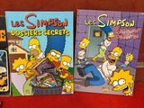 trois livres de la série des Simpsons sont assis sur un canapé rouge