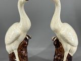 une paire d'oiseaux en céramique, l'un blanc et l'autre marron, perchés sur une souche d'arbre