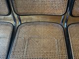 four black metal chairs with wicker seats in a living room