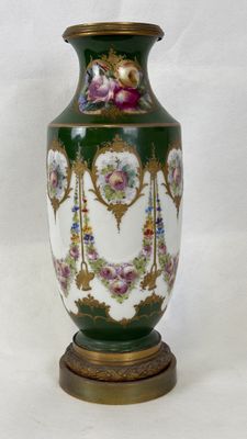 a green vase with flowers on it sitting on a table
