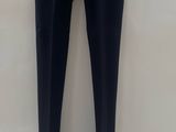 black pants hanging on a hanger against a white wall