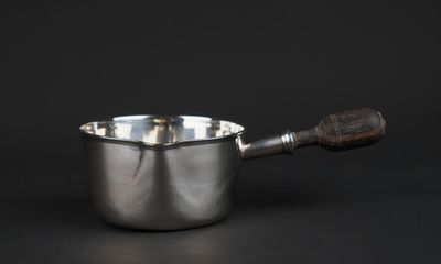 a silver saucepan with a wooden handle on a black background