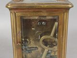 une petite horloge en laiton avec une clé à l'intérieur