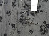 gray shirt with black flowers and a white tag on it