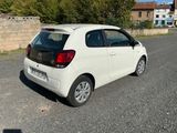 a small white car that is parked on the side of the road