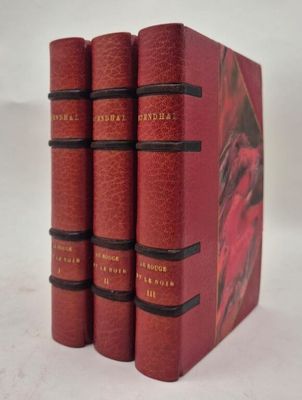 trois livres rouges sont empilés sur une surface blanche