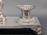 a silver vase and a silver candle holder on a stand