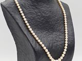 a close up of a mannequin with a pearl necklace on it