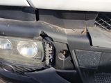 the front end of a white truck with a dent in it