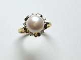 gros plan d'une bague en perles et diamants sur une surface blanche