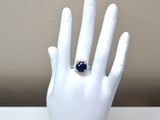 a hand with a ring on it that has a blue stone in it