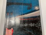 the book is sitting on a table with a blurry image of a train passing by