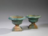deux vases verts posés l'un sur l'autre sur une surface blanche