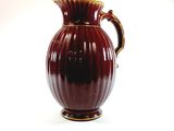 a red vase that is sitting on a white surface