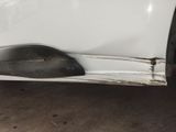 the front bumper of a white car with scratches on it