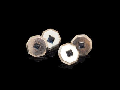 deux boucles d'oreilles à clous argentées et noires sur un fond noir