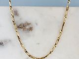 un collier à chaîne en or posé sur une surface en marbre