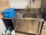 un évier dans une petite cuisine, avec une poubelle bleue posée sur le plan de travail