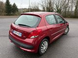 La voiture rouge est garée sur le parking près des arbres.