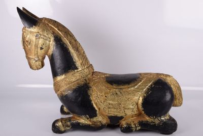 un cheval noir et doré posé sur une surface blanche