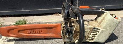 une tronçonneuse posée par terre à côté d'un objet orange