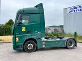 a green semi truck parked in front of a building