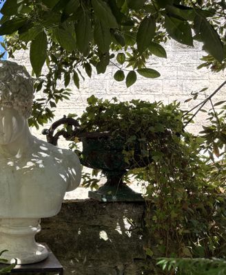a statue of a man sitting on top of a stone wall