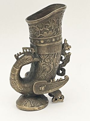 un vase en argent orné d'un dragon sur fond blanc