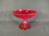 un bol en verre rouge posé sur un socle, sur fond gris